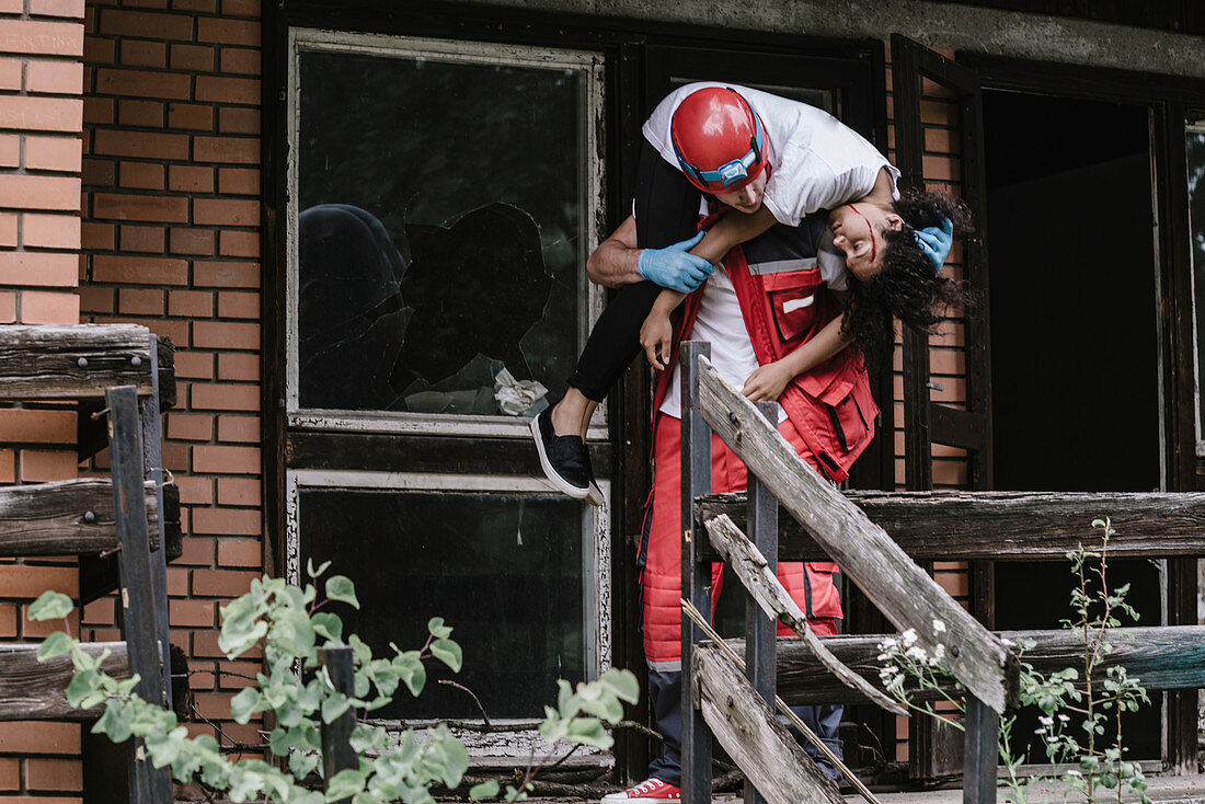 Rescue worker carrying woman out of damaged house