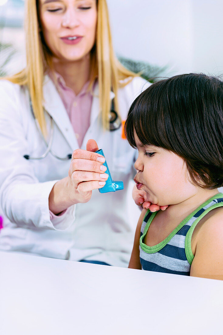 Paediatrician helping boy with asthma inhaler