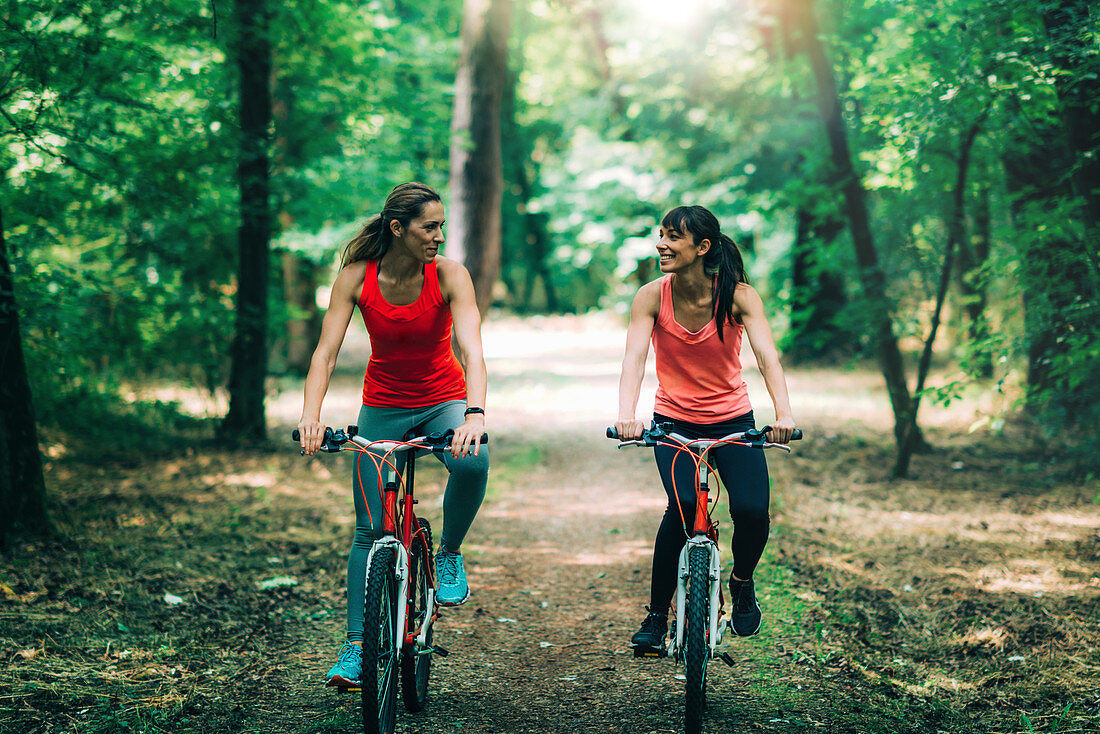 Women riding bikes together in a park