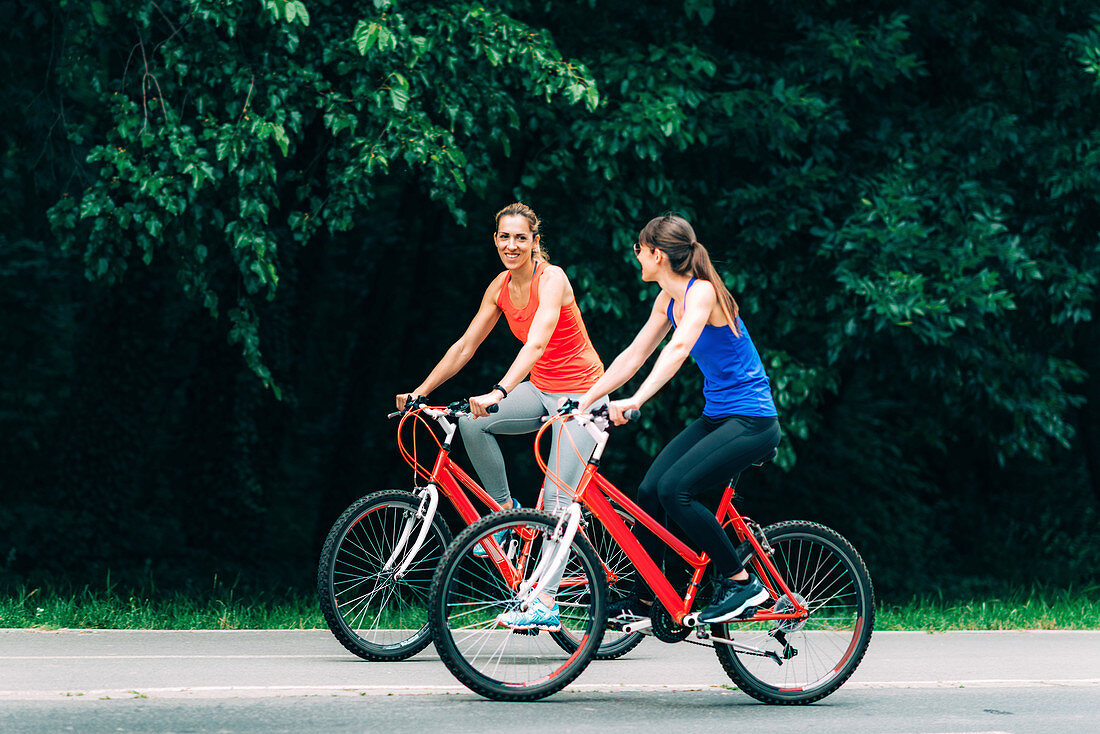 Women riding bikes together in a park