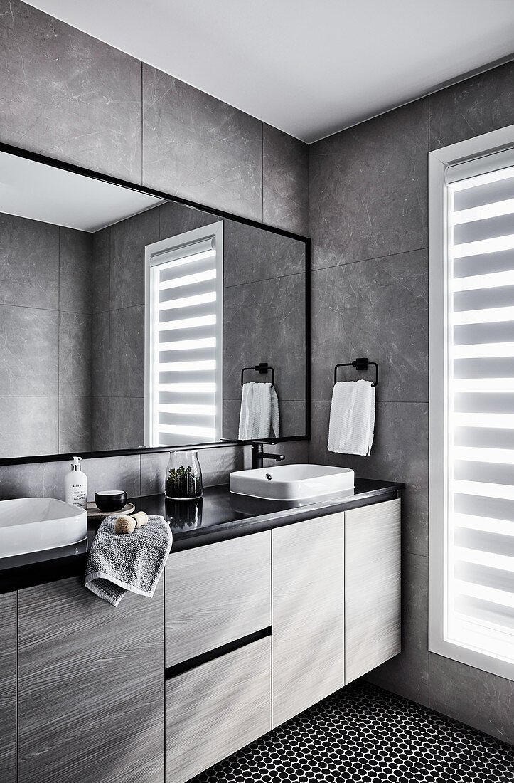 Elegantes Badezimmer mit Waschtischmöbel und grauen Wandlfiesen