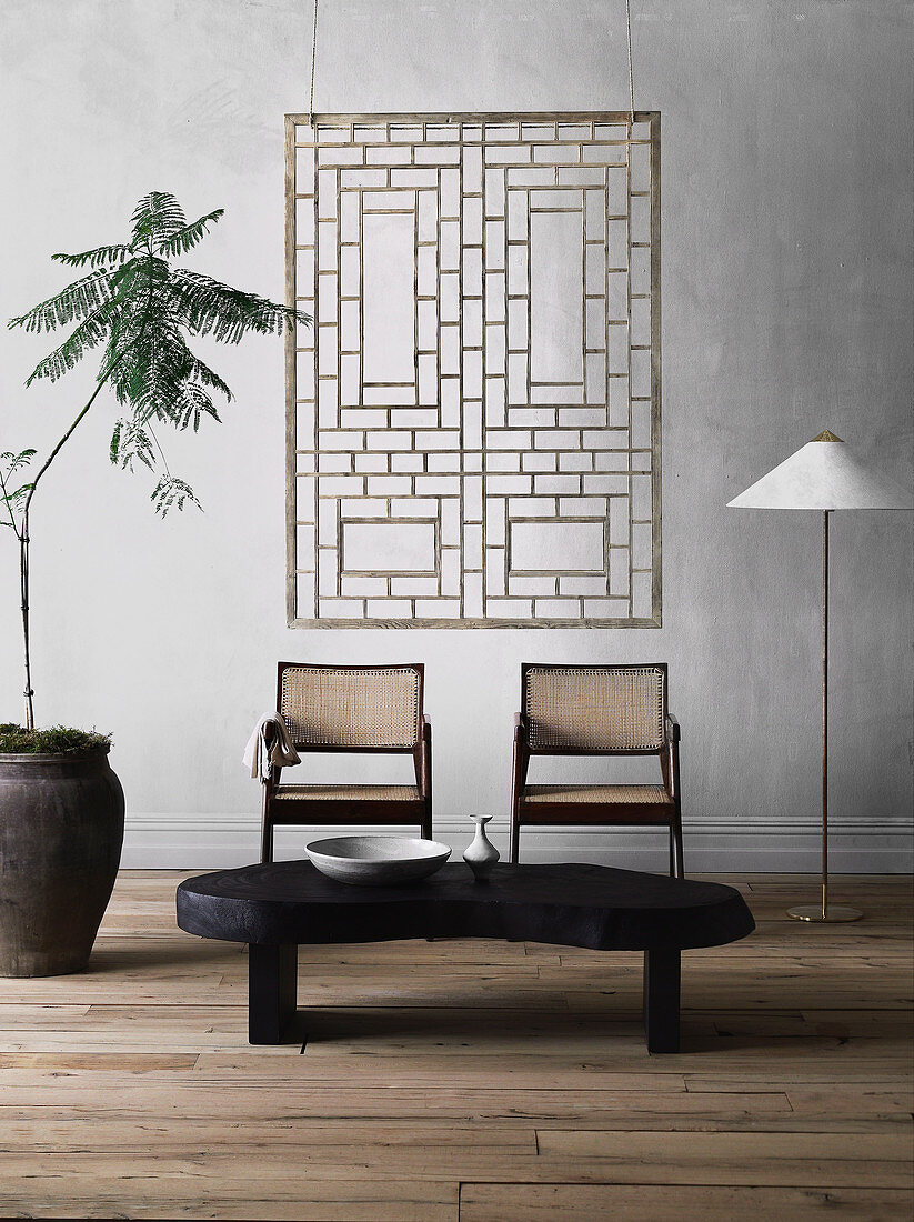 Organically shaped coffee table, two chairs, floor lamp and house plant, modern art on the wall