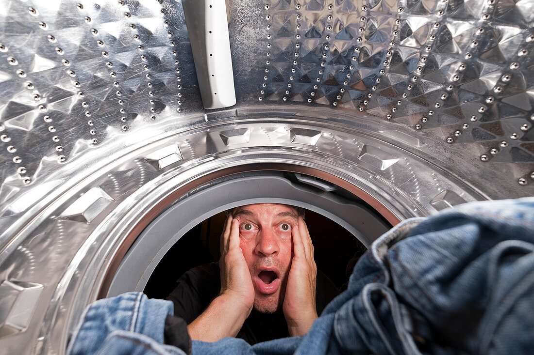 Shocked man looking in washing machine
