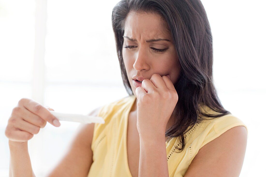 Worried woman looking at pregnancy test