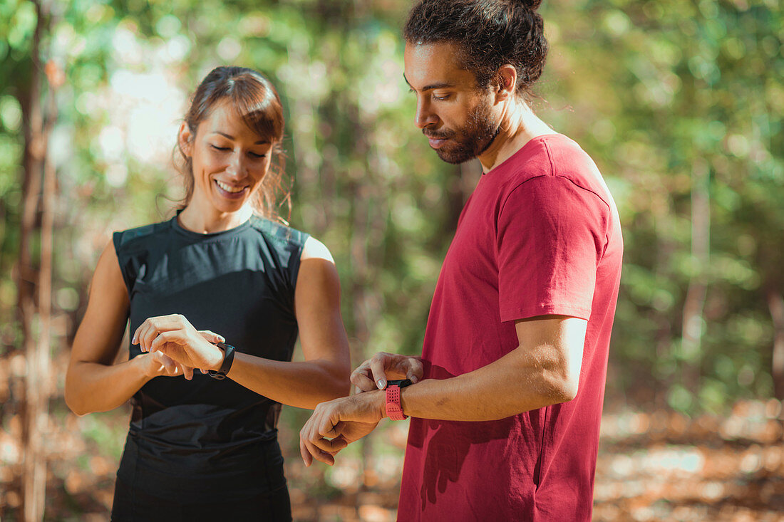 Young couple looking at their smart watches after training