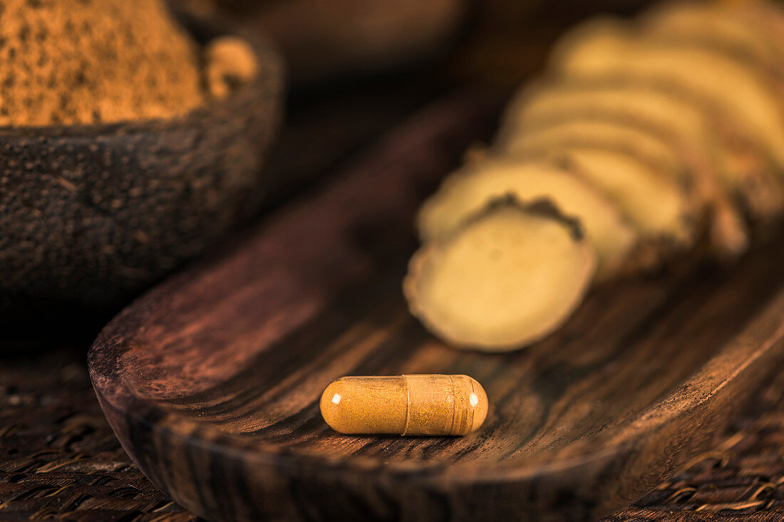 Ginger herbal supplement capsule and sliced ginger root