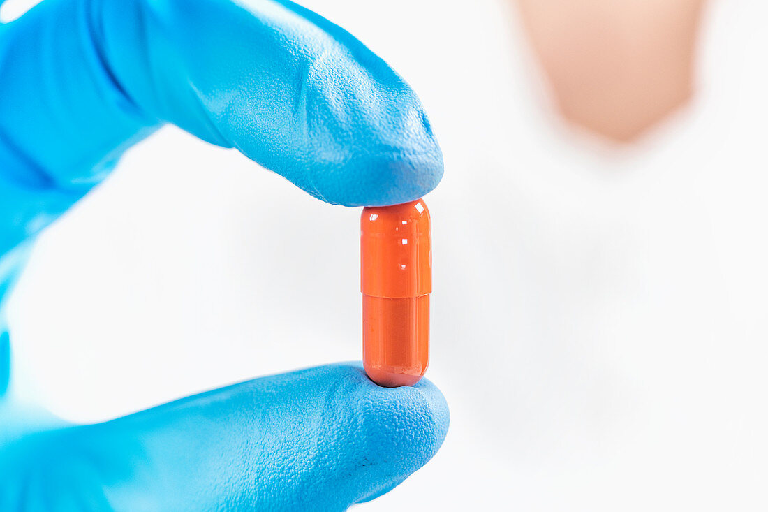 Scientist holding orange pill
