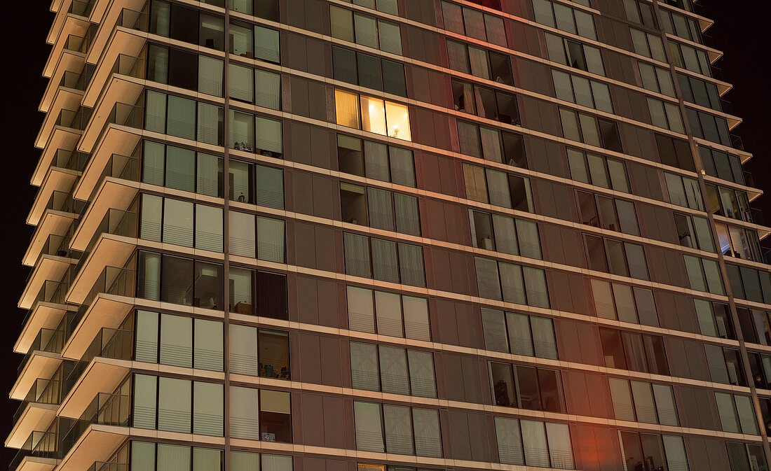 Single lit window in modern apartment block