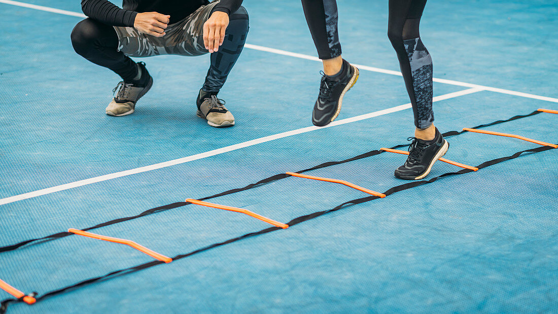 Young woman exercising with agility ladder