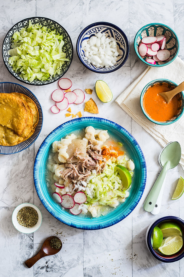 Mexikanische Hominy-Suppe mit Schweinefleisch und verschiedenen Toppings