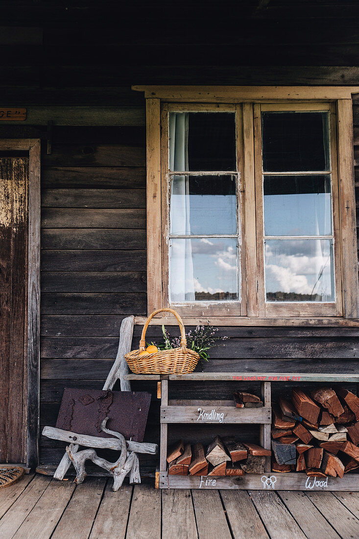 Shelf with firewood under the mullioned window on the veranda