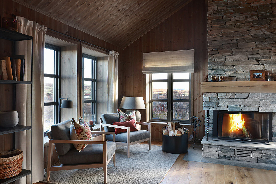 Armchairs in front of fire in cosy cottage interior