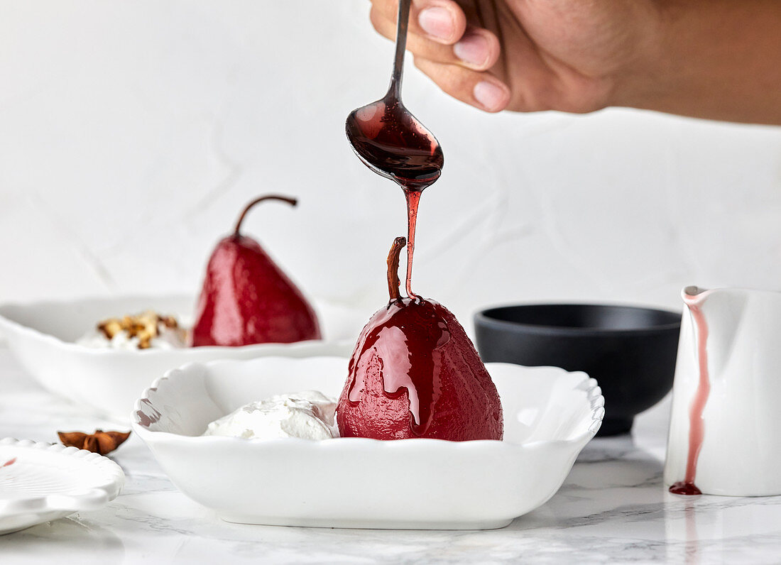 Pears poached in red wine sauce with spices served with mascarpone and cream