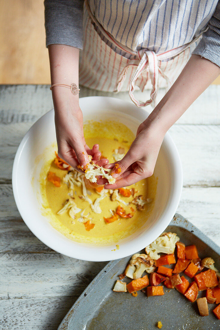 Kind belegt Backblech mit Blumenkohl und Kürbis