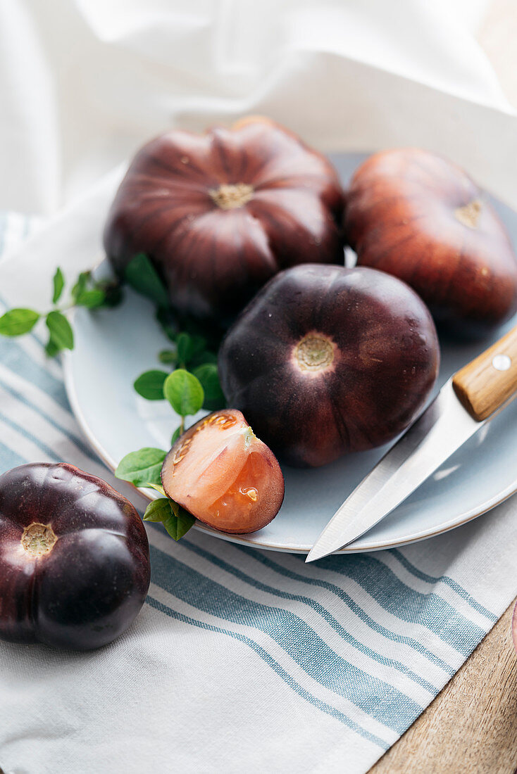 Frische schwarze Tomaten mit Messer auf Teller