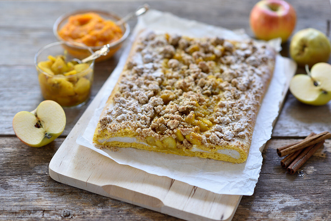Vegan pumpkin and quark yeast dough strudel with apple and pear compote and oat and date crumbles on a wooden board