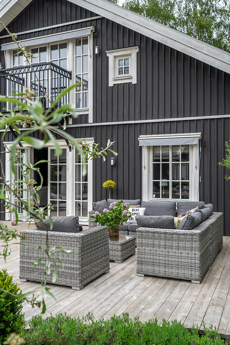 Pale grey seating on terrace outside wooden house