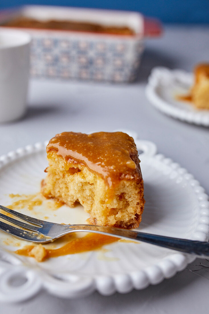 Half eaten slice of Tres Leches cake, covered with caramel sauce and sprinkled with sea salt