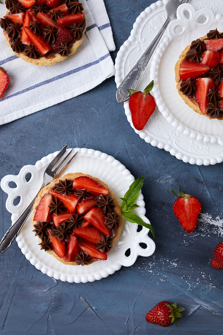 Mini tart with strawberry jam, served with fresh strawberries and chocolate ganache