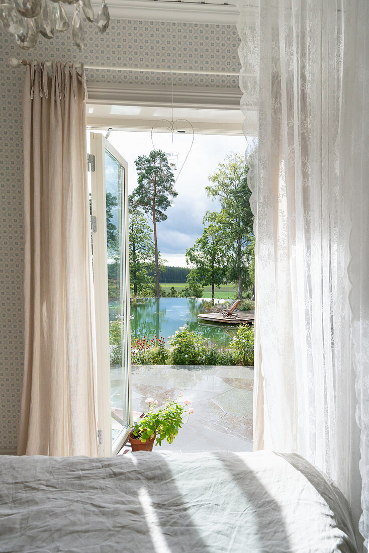 View from bedroom into summery garden with lake