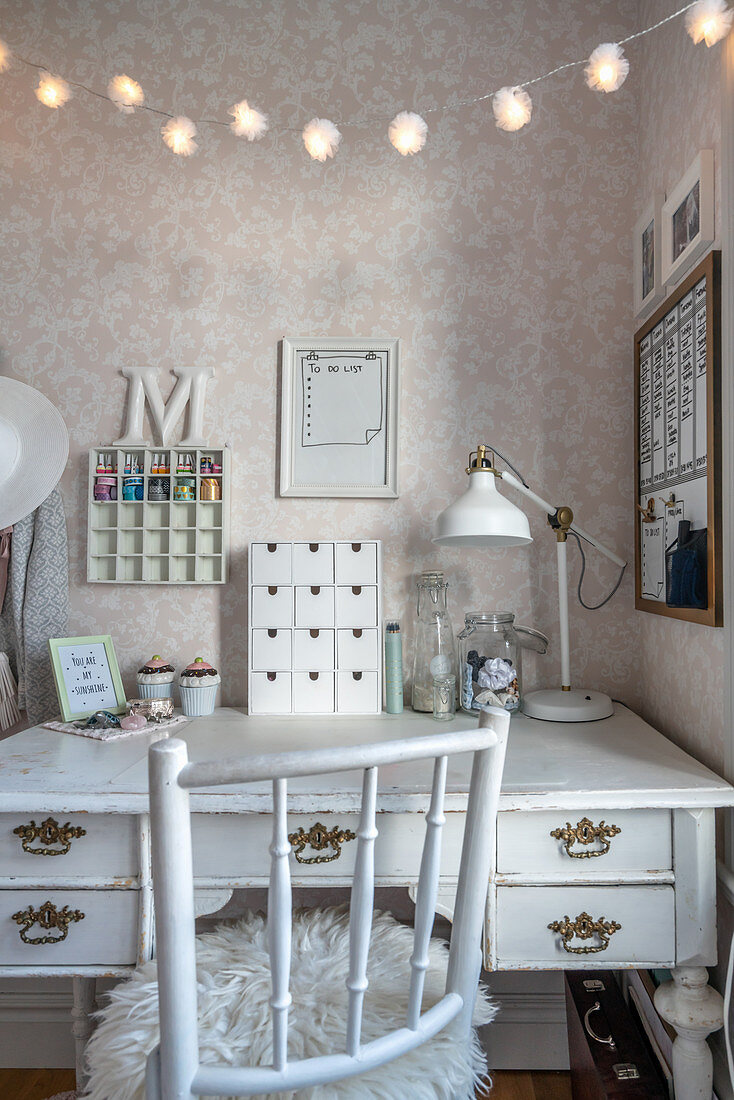 Spoke-back chair at vintage-style desk below fairy lights