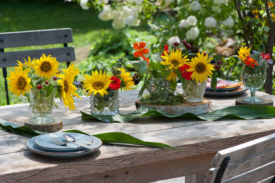 Kleine Sträuße mit Sonnenblumen und Kapuzinerkresse als Tischdekoration