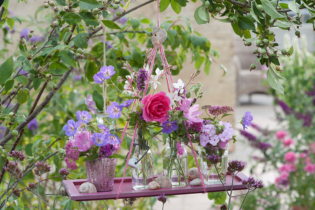 Small bouquets of roses, cranesbill, flame flower, betony, candle and mallow as a hanging decoration