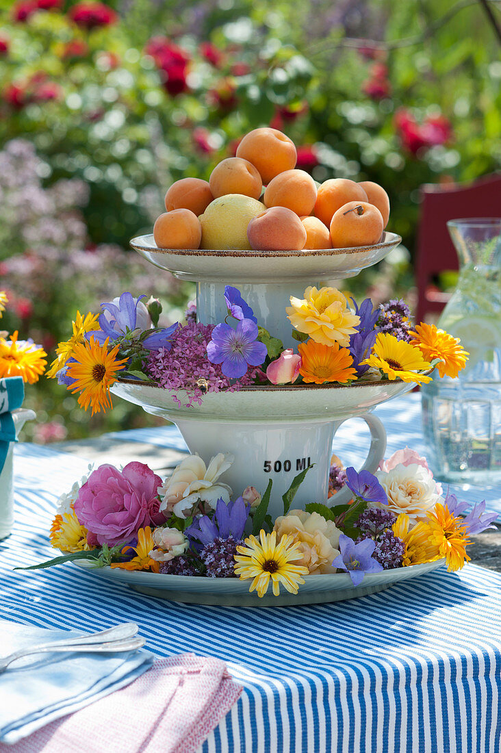 Etagere mit bunten Blüten und Aprikosen als Tischdeko