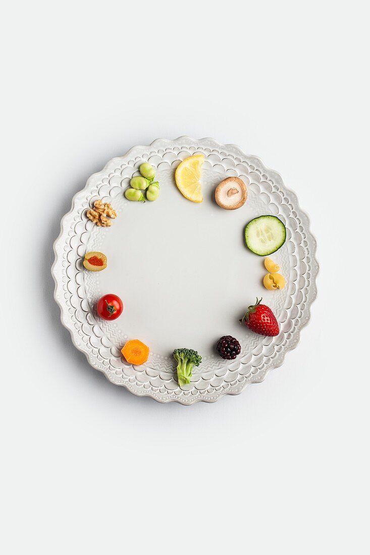 Plate with fresh fruits and vegetables arranged as a clock