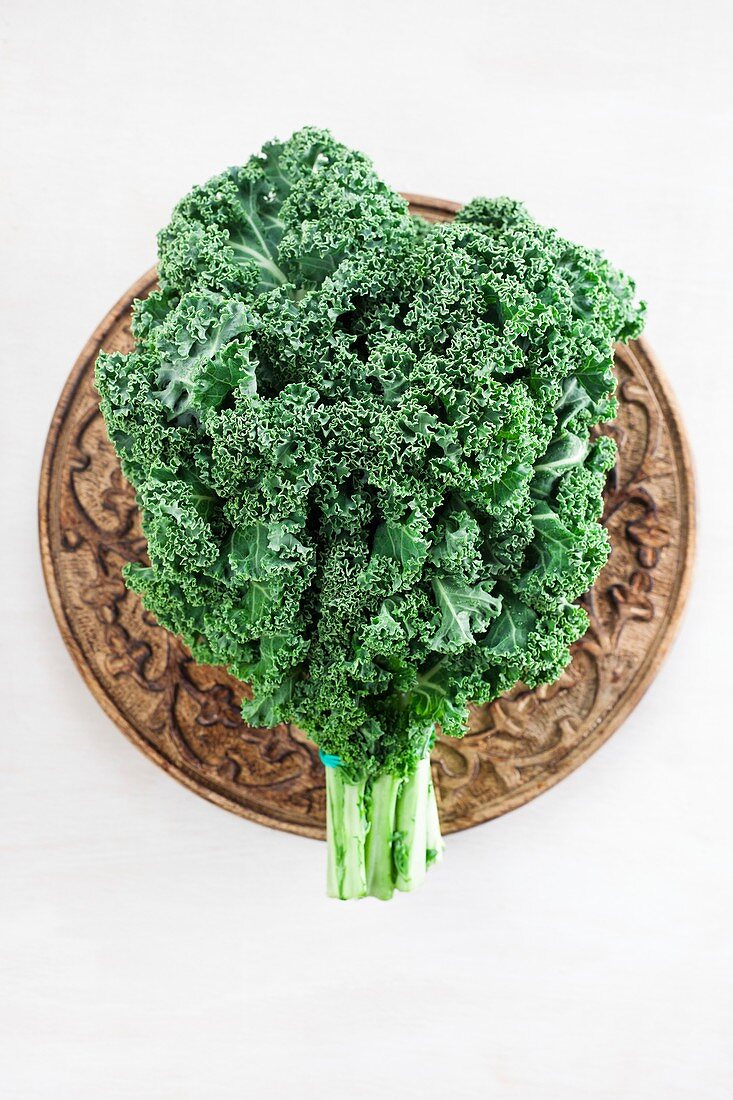 Curly kale leaves on a wooden plate