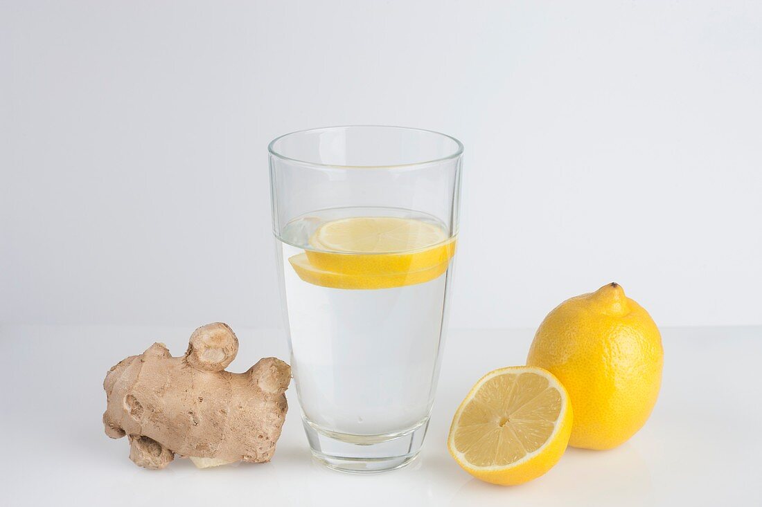 A glass of water with fresh lemon slices and ginger