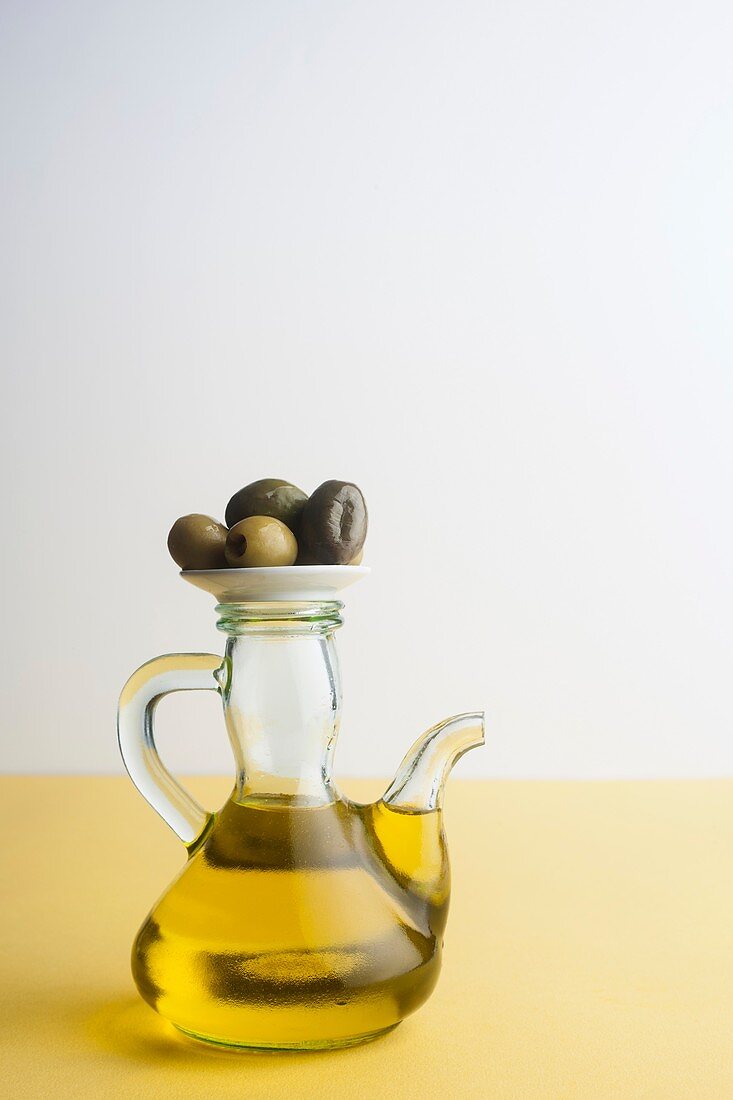 Jug of olive oil with olives