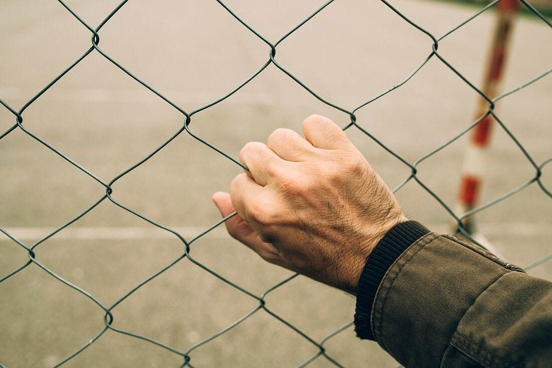 Male hand on chainlink fence