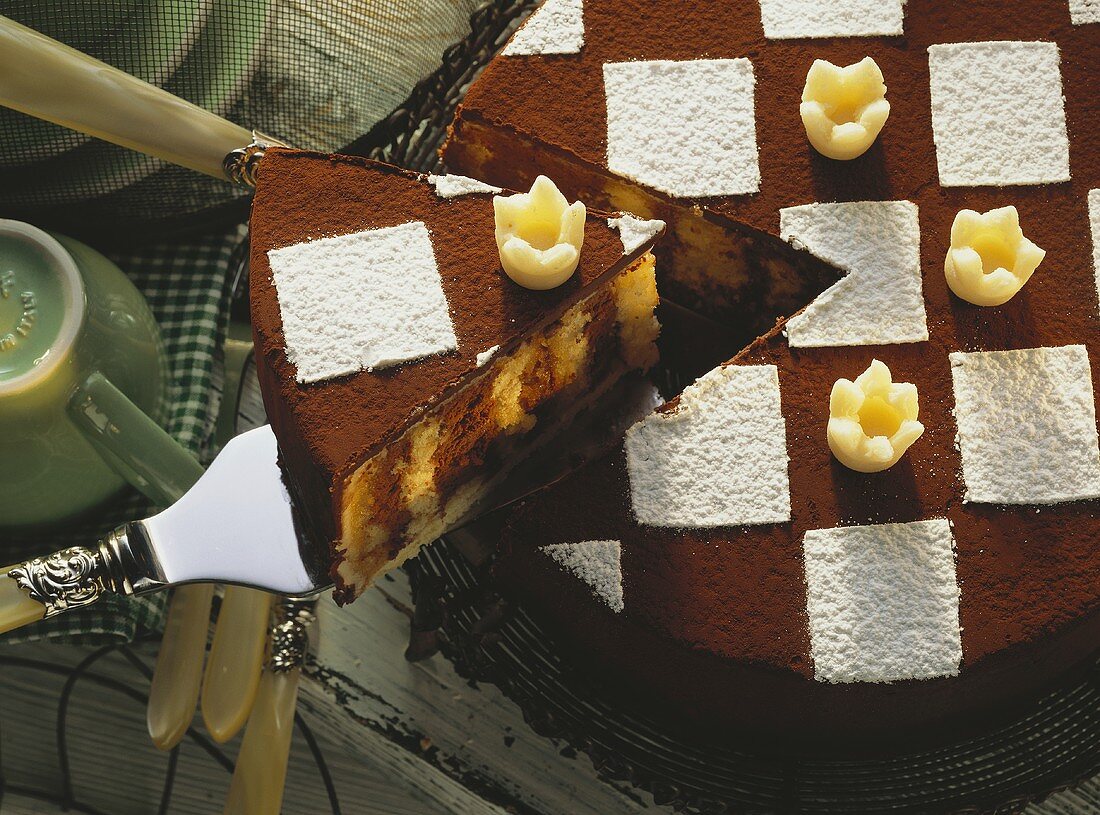 Chess board cake with marzipan crowns, a piece cut