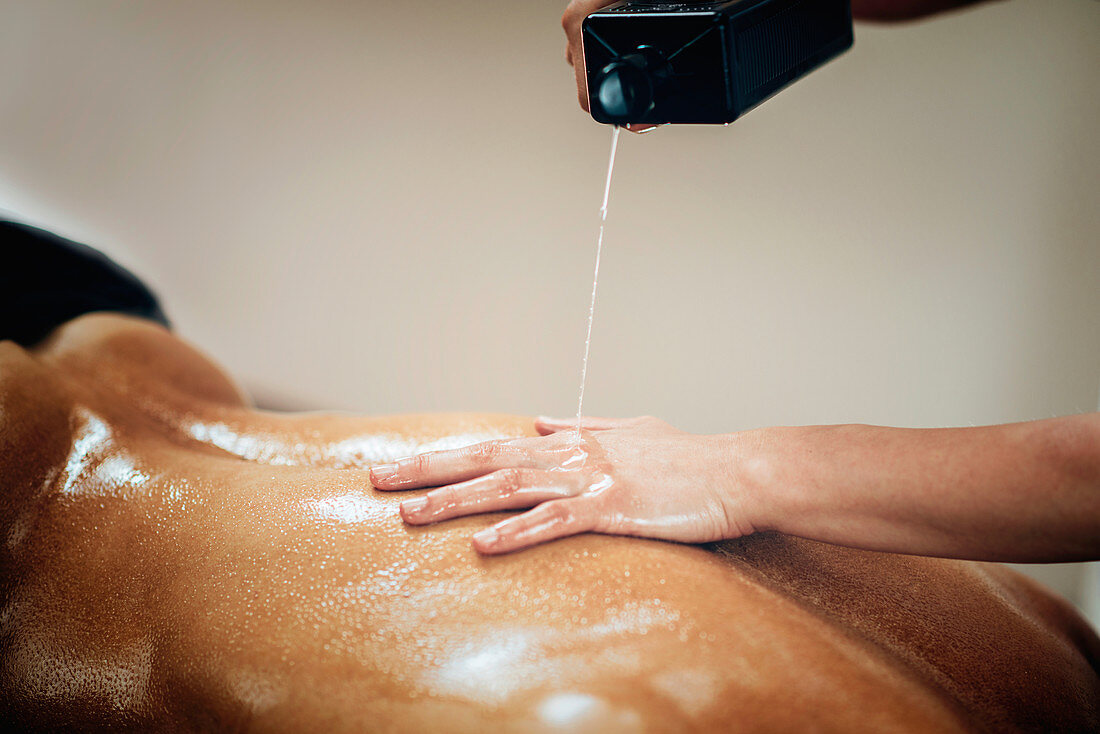 Physical therapist pouring massage oil