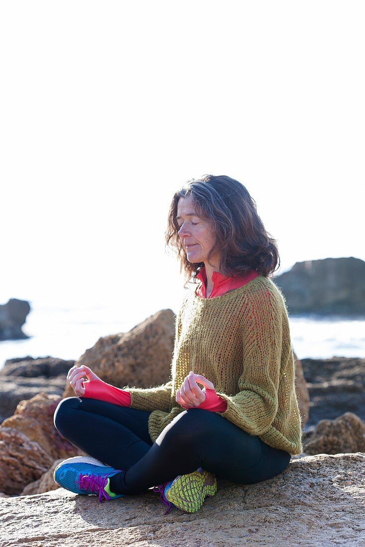 Woman meditating next to the sea