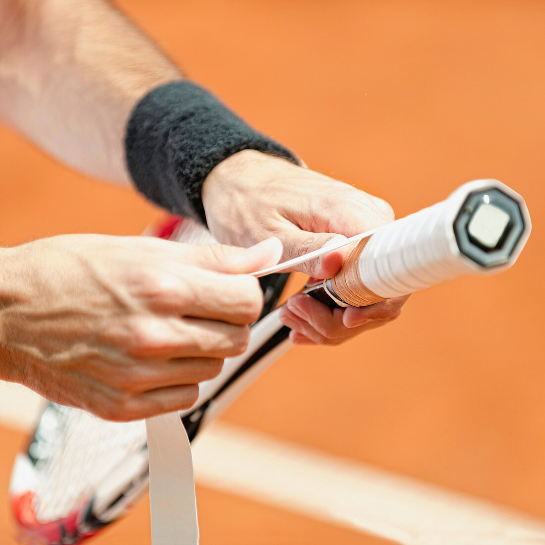 Player putting new grip tape on tennis racket