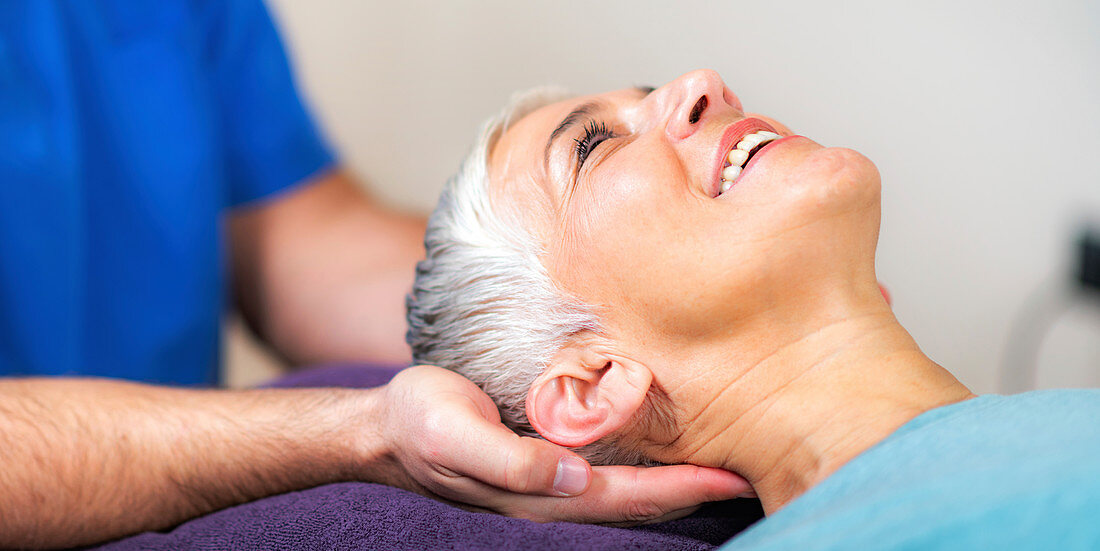 Physical therapist stretching senior woman's neck