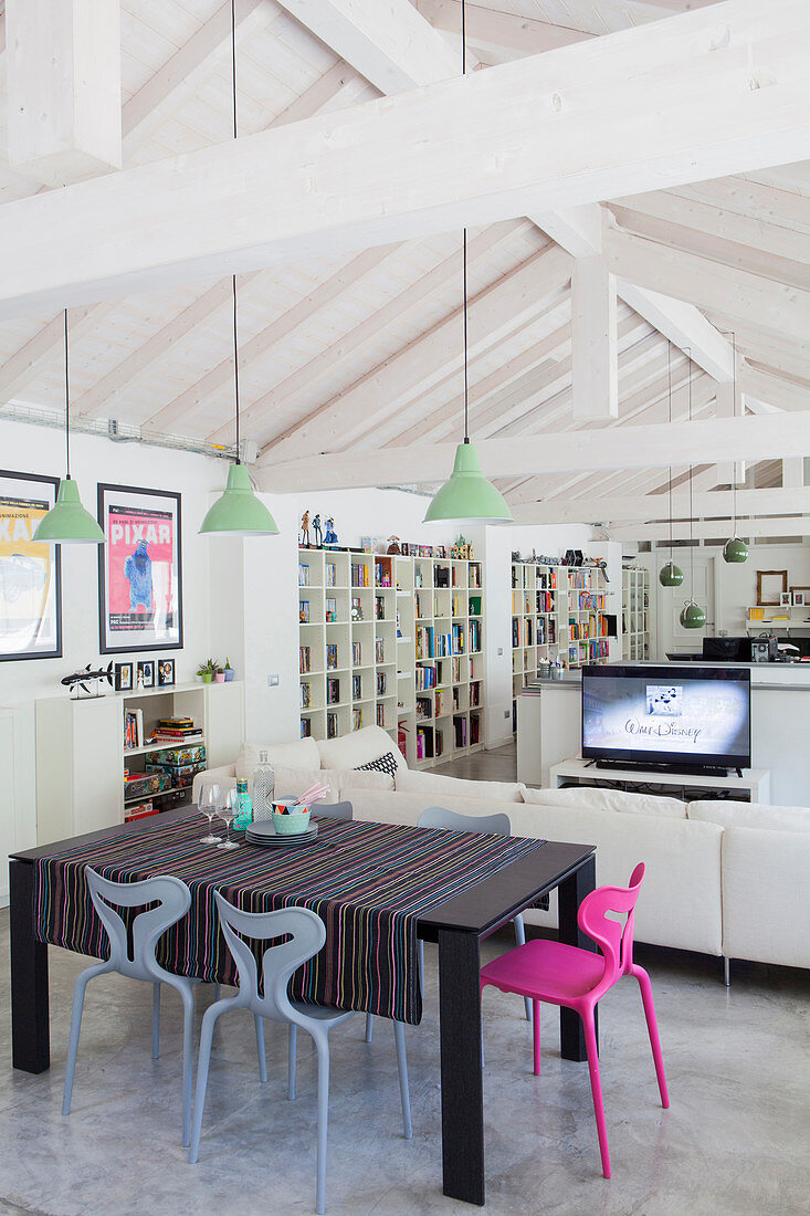 Dining table and living area in loft apartment with open roof structure