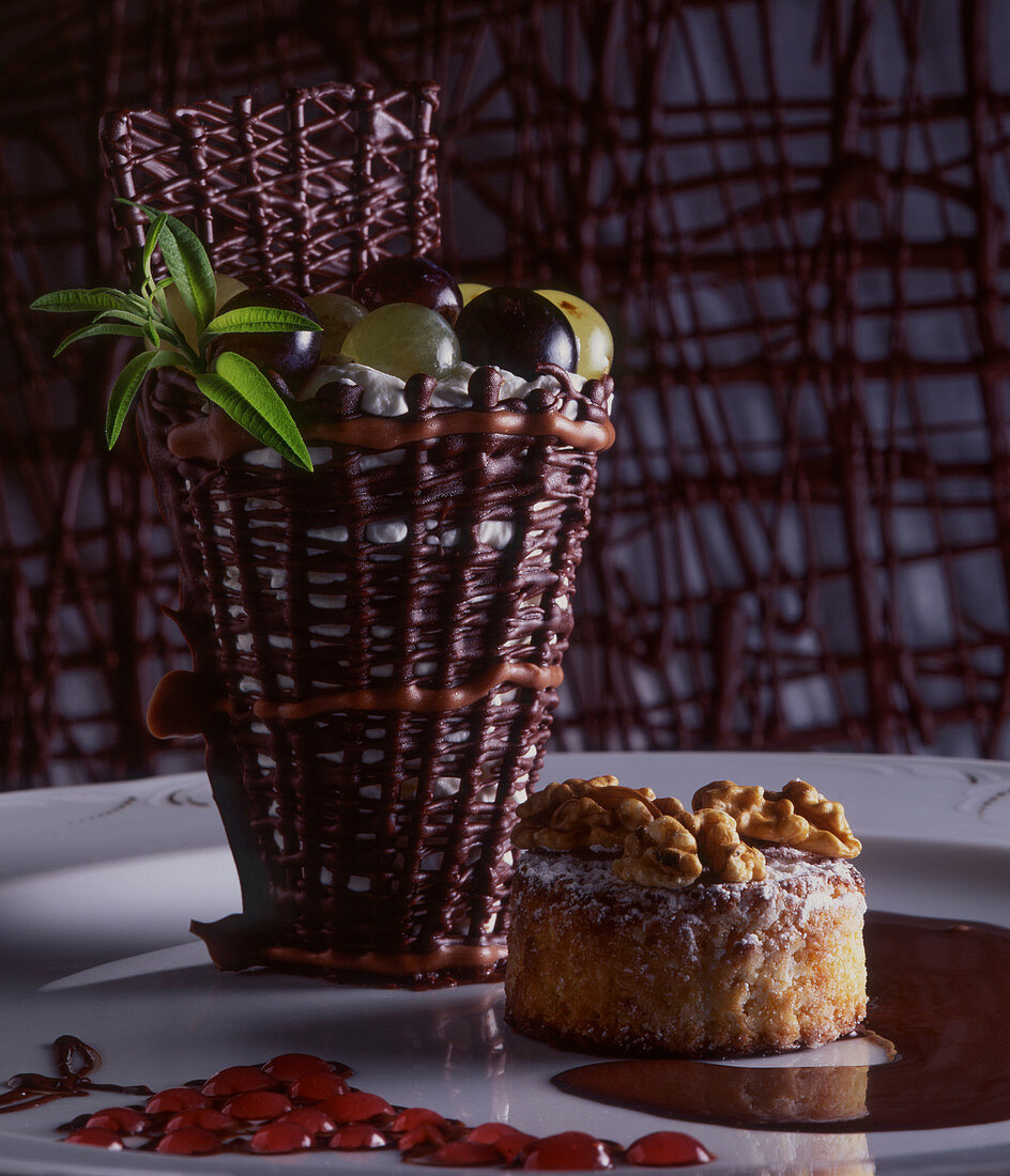 A chocolate basket with grapes and a mini walnut cake
