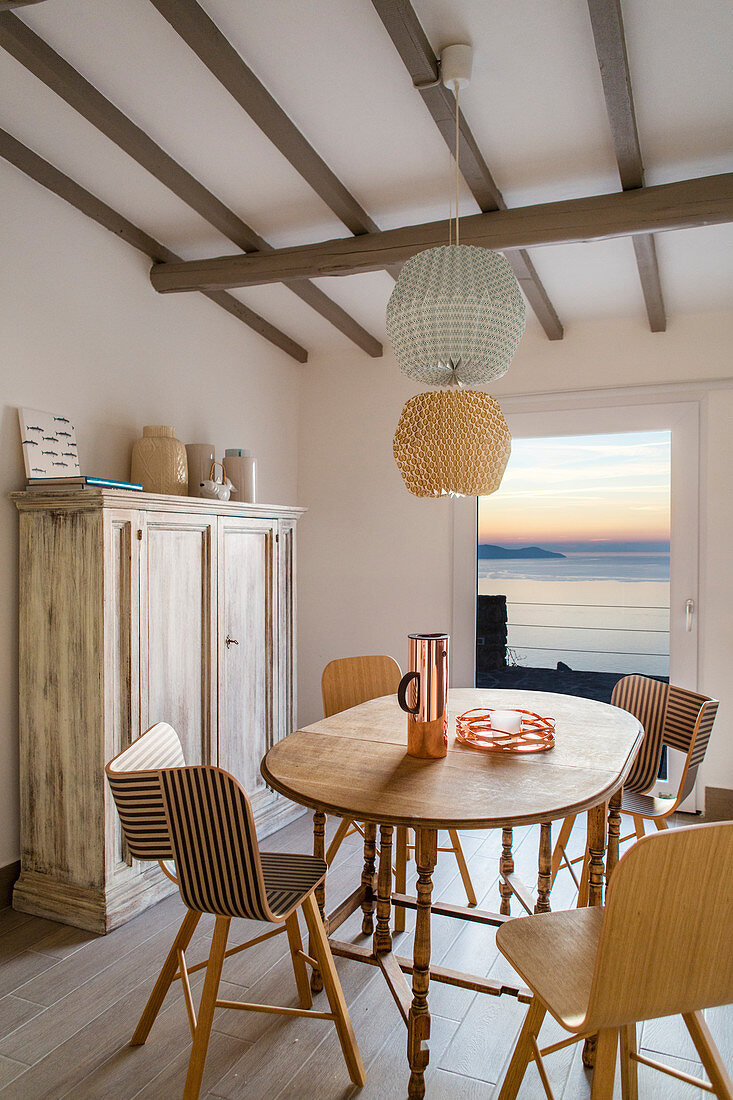 Designerstühle am Esstisch mit Blick aufs Meer bei Abendstimmung