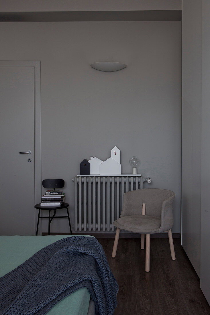 Upholstered chair in front of radiator in bedroom