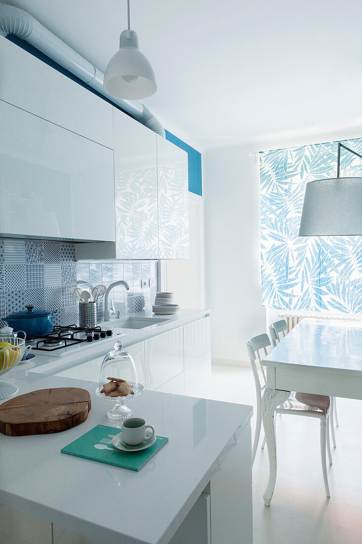 White fitted kitchen with counter, table and chairs