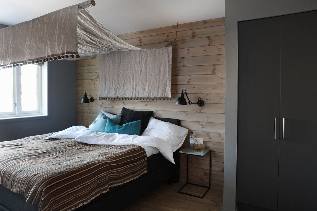 Bedroom in earthy shades with canopy over bed and wood-clad walls