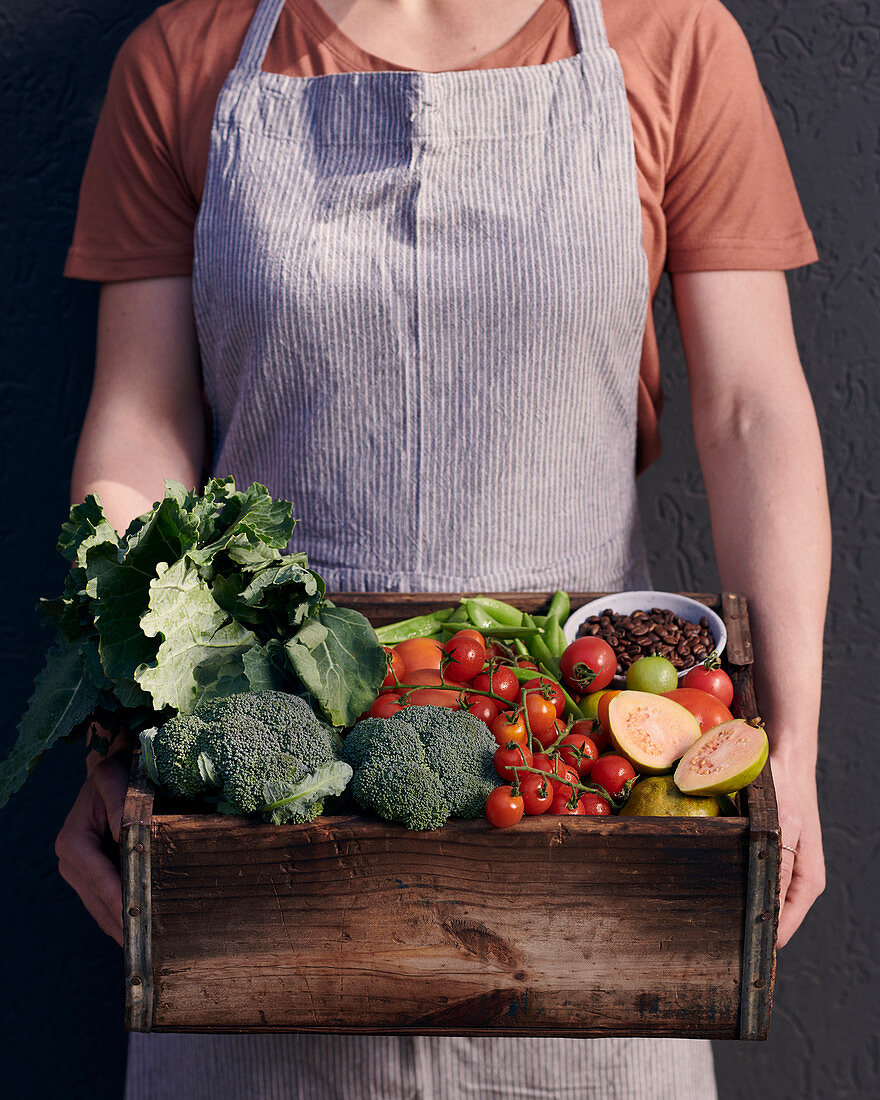 A wooden box with vegetables, fruit and coffee beans