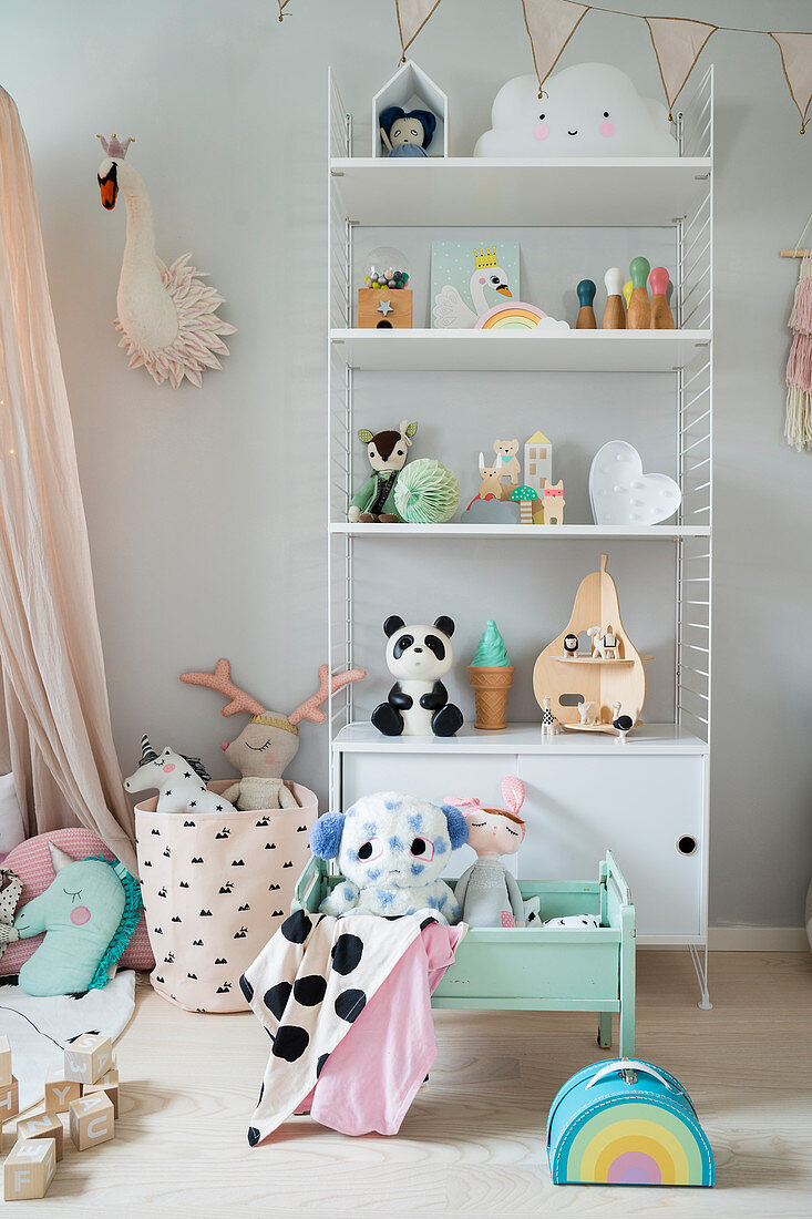 Offenes Wandregal mit niedlicher Kinderdeko in pastellfarbenem Mädchenzimmer