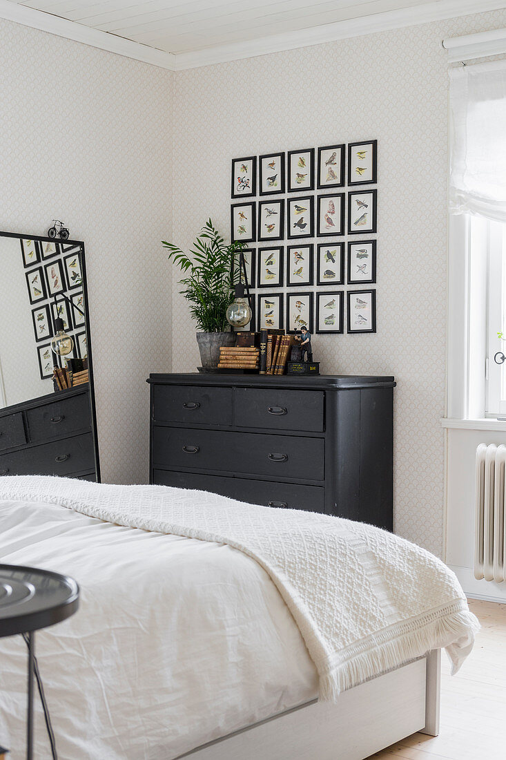 Pictures of birds arranged in a square above chest of drawers in bedroom