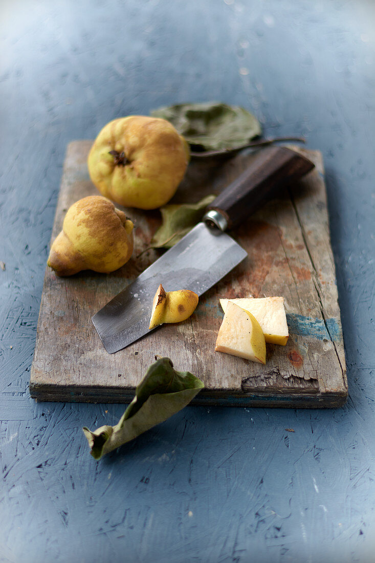 Quince on a wooden board with a chef's knife