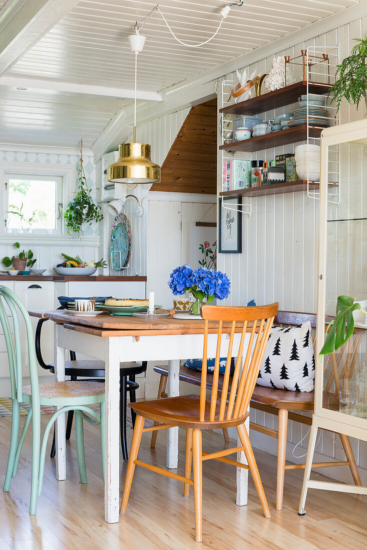 Spoke-back bench and various chairs around table in kitchen-dining room