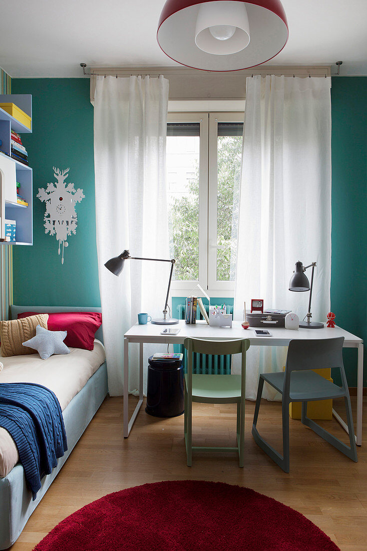 Bed in corner and desk with two chairs below window in sibling's bedroom